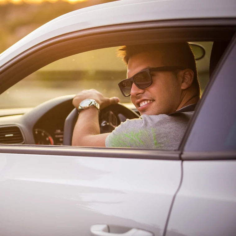 A sedan on a two lane highway above the Pacific coast