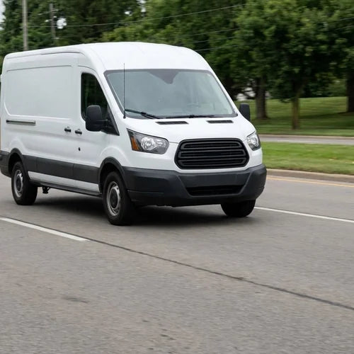 A plain white service van travelling along a suburban road